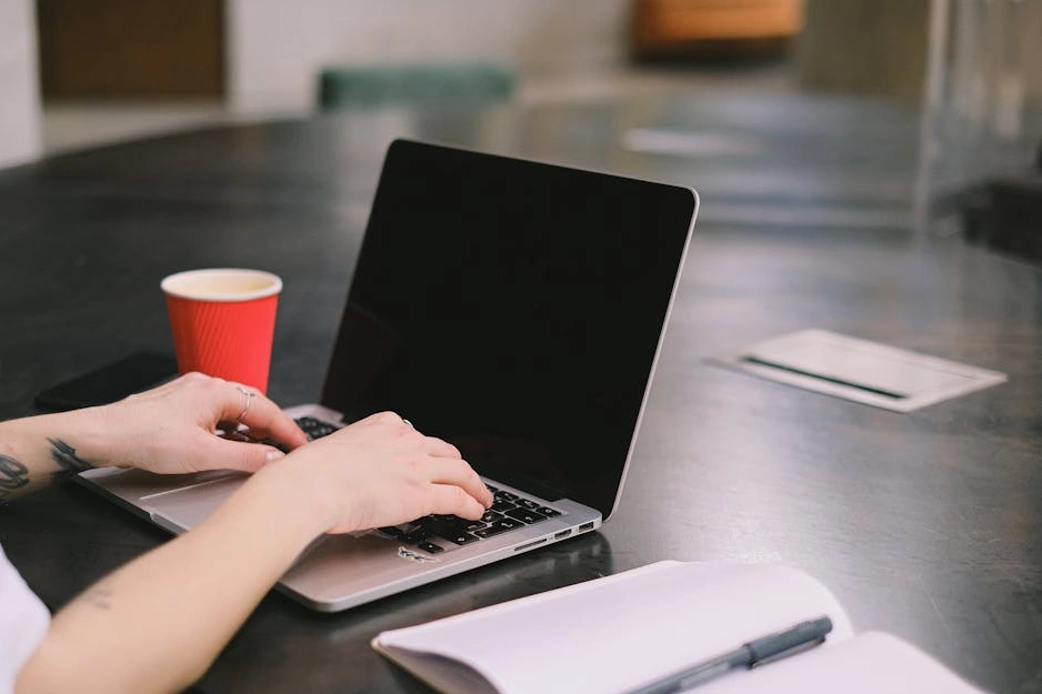 Studente sorridente che lavora al computer in un ambiente moderno.